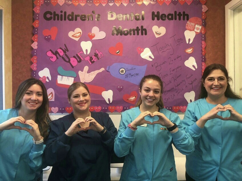Kidzdent team members holding their hands in the shape of hearts for children's dental health month